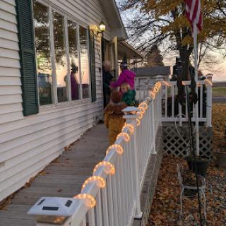 A cozy house adorned with festive lights, showcasing the beauty of autumn during sunset.