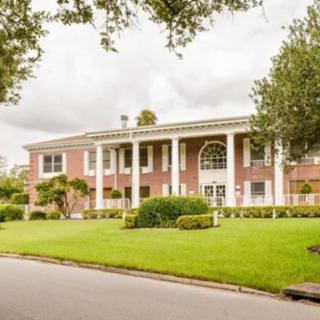 A large residential building with a well-maintained lawn and prominent columns.