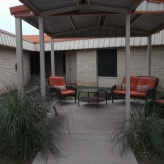 An outdoor patio area with cushioned chairs and a small table under a gazebo.