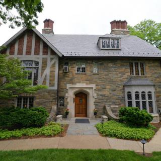 A charming Tudor-style stone house with beautiful landscaping.