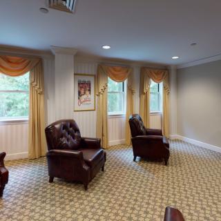 A cozy waiting room with armchairs and windows adorned with curtains.
