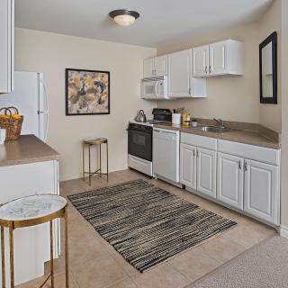 A modern apartment kitchen with white cabinetry and standard appliances.
