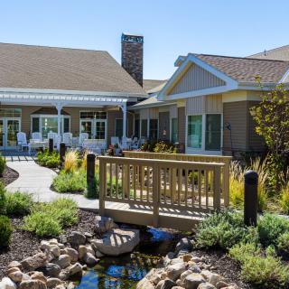 A picturesque garden with a wooden bridge leading to a charming building.