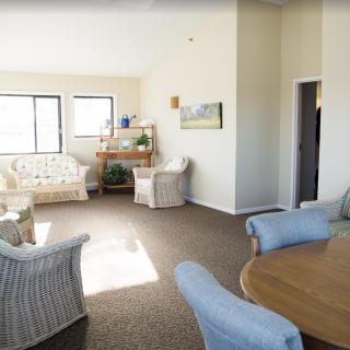 A bright and spacious living room with various seating options and natural light streaming through the windows.