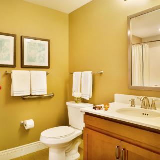 A well-organized bathroom with a toilet, sink, mirror, and artwork on the walls.