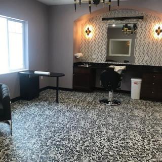 A chic salon interior with stylish lighting, patterned carpet, and a large mirror.