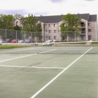 A view of empty tennis courts surrounded by residential buildings and greenery.