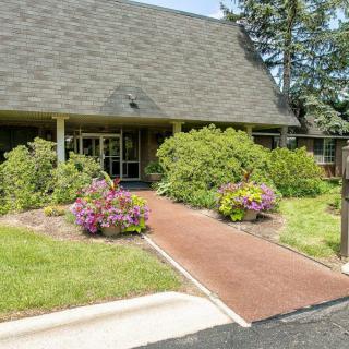 A garden pathway leads to the entrance of a building, surrounded by lush greenery and colorful flowers.