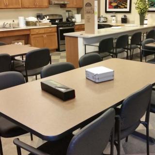A well-equipped office break room with tables and chairs, featuring a kitchen area with appliances.
