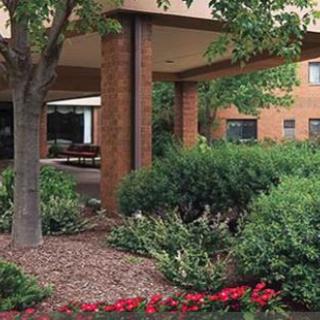 A landscaped area with trees and shrubs surrounding a brick building.