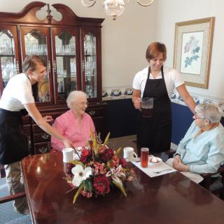 Caregivers attending to seniors during a dining experience.
