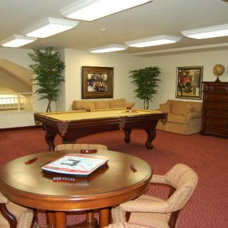 A cozy game room featuring a billiards table, seating area, and warm interior decor.