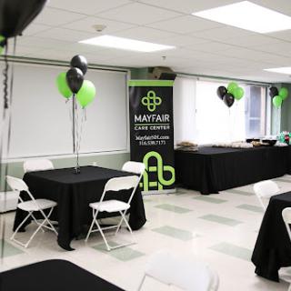 A well-decorated event space featuring black and green balloons, tables, and a promotional banner.