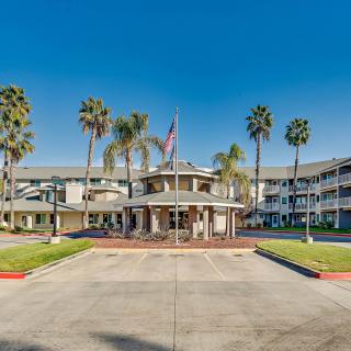 A hotel building with palm trees and an entrance driveway, featuring a flag at the entrance.
