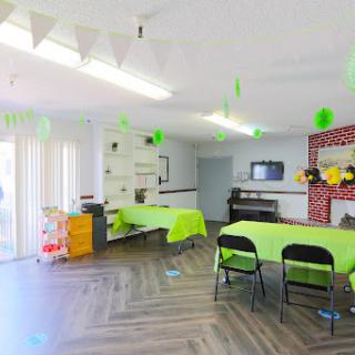A brightly decorated classroom setup with green tables and colorful wall decorations.