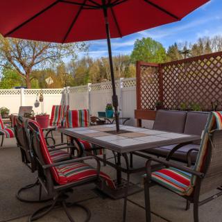 A cozy backyard patio with a table and chairs under a red umbrella, perfect for outdoor relaxation.