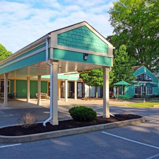 An empty drive-thru building surrounded by trees on a sunny day.