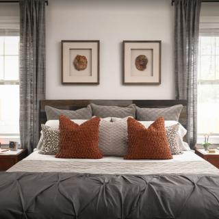 A cozy and stylish bedroom with a neatly arranged bed, featuring decorative pillows and framed artwork above the headboard.