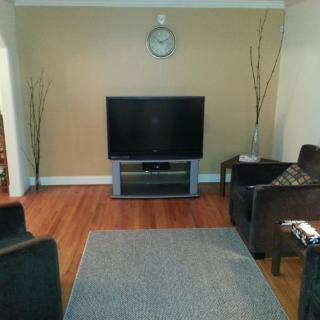 A minimalist living room with a television, sofas, and a clock on the wall.