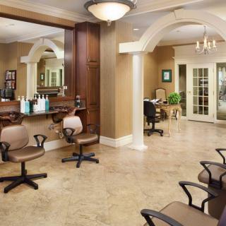 A spacious and well-lit salon interior featuring styling chairs, mirrors, and hair products.