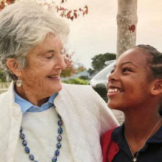 An elderly woman and a young girl sharing a joyful moment outdoors.