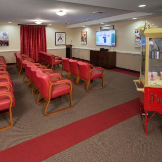 A small movie theater with red chairs and a popcorn machine.