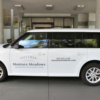 A branded white van parked in front of a building entrance.