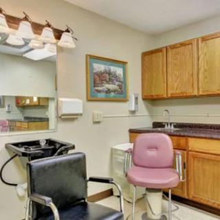A small salon setup with chairs, mirror, and cabinets.