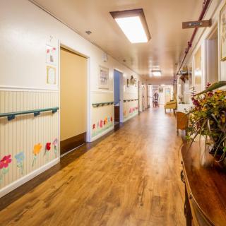 A brightly decorated hospital hallway with wooden flooring, likely part of a children's ward.