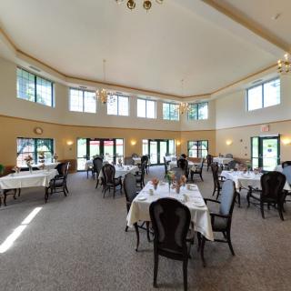 A spacious dining area with elegantly set tables and large windows letting in natural light.
