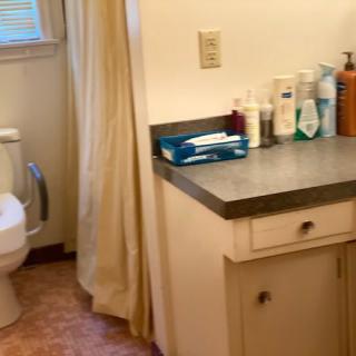 A bathroom with a toilet, sink, and various toiletries on the counter.