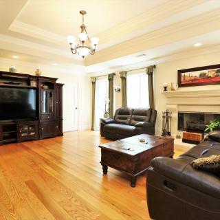 A cozy living room with hardwood floors, leather sofas, a coffee table, and a fireplace.