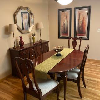 A cozy dining room featuring an elegant wooden dining table and chairs, complemented by stylish wall art and lamps.