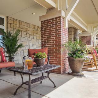 A cozy porch with comfortable seating and potted plants, perfect for relaxation.