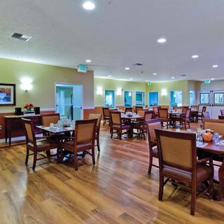A spacious dining area with neatly arranged tables and chairs, featuring a warm ambiance and wooden flooring.