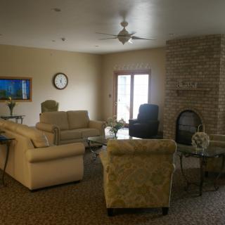 A cozy living room with sofas, a fireplace, and a TV mounted on the wall.