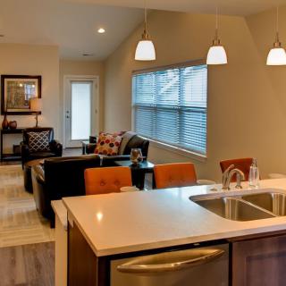 A modern open floor plan featuring a kitchen and living room with stylish furnishings and lighting.