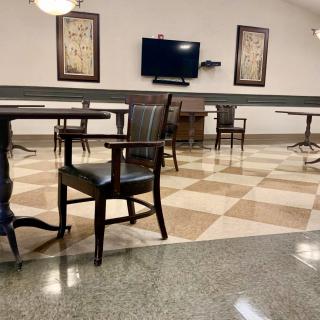 A spacious room with chairs and tables, featuring a television and decorative wall art.