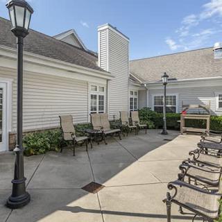 A sunny outdoor patio area with chairs and lamp posts next to a building.