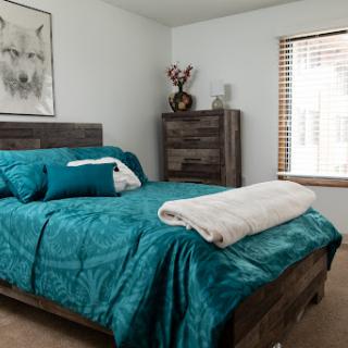 A beautifully decorated bedroom featuring teal bedding, wooden furniture, and a cozy atmosphere.