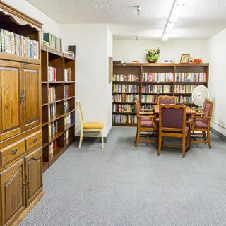 A cozy reading room with bookshelves, a table, and chairs.