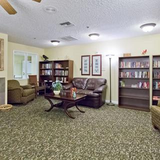 A cozy living room with bookshelves, a sofa, chairs, and a coffee table on a patterned carpet.