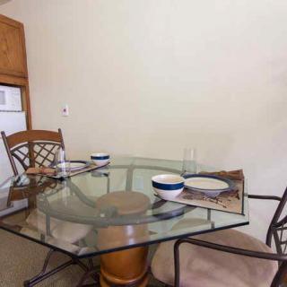 A glass dining table with chairs and dinnerware set in a kitchen area.