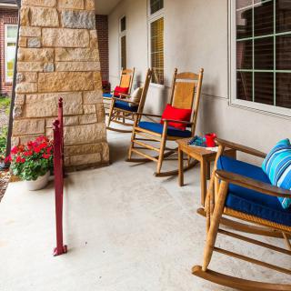 A cozy porch with rocking chairs adorned with cushions, offering a relaxing outdoor seating area next to vibrant flowers.