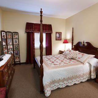 A cozy bedroom featuring a four-poster bed with quilted bedding, surrounded by vintage decor and traditional furnishings.