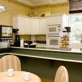 A cozy kitchen interior with white cabinets, built-in appliances, and a small dining table.