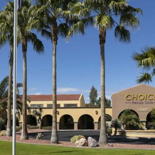 A commercial building surrounded by tall palm trees under a clear blue sky.