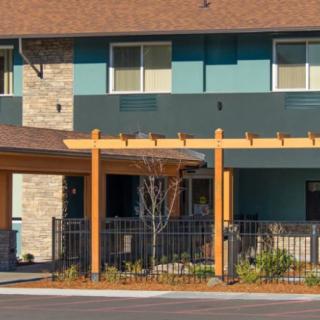 A modern residential building with a landscaped front yard and a fence.