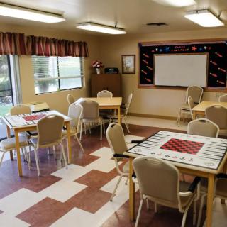An empty classroom with tables and chairs arranged, featuring a projector screen.
