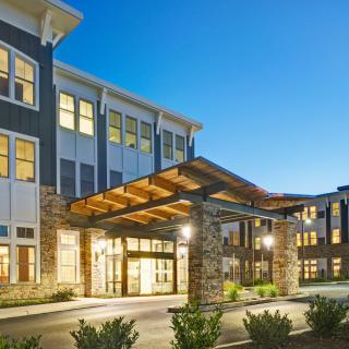 A modern building with illuminated windows and a welcoming entrance at dusk.